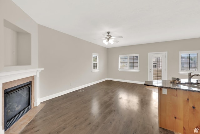 602 E Wyngate Pointe Ln S, Draper, UT 84020 - unfurnished living room featuring a ceiling fan, a tiled fireplace, dark wood-style flooring, and healthy amount of natural light