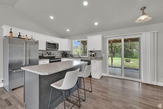 6337 S Coybrook Dr, Taylorsville, UT 84129 - kitchen with stainless steel appliances, lofted ceiling, backsplash, a kitchen island, and white cabinets