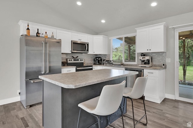 6337 S Coybrook Dr, Taylorsville, UT 84129 - kitchen featuring stainless steel appliances, a center island, white cabinets, light wood finished floors, and backsplash