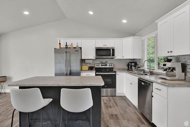 6337 S Coybrook Dr, Taylorsville, UT 84129 - kitchen with stainless steel appliances, lofted ceiling, a breakfast bar area, light wood finished floors, and a kitchen island