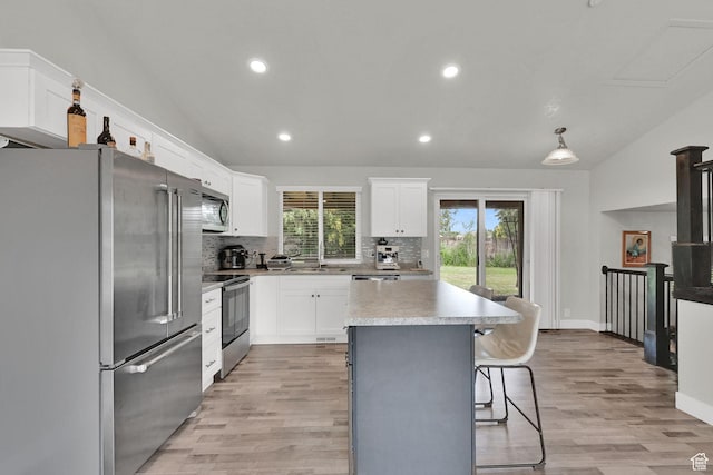6337 S Coybrook Dr, Taylorsville, UT 84129 - kitchen with stainless steel appliances, lofted ceiling, decorative backsplash, light wood-style floors, and a kitchen island