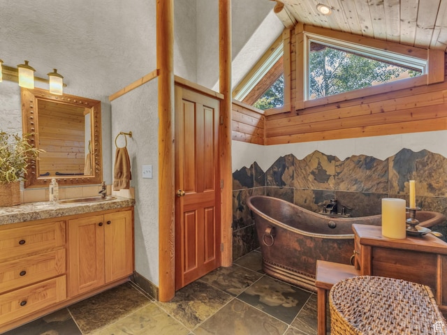 8998 Timphaven Rd, Sundance, UT 84604 - full bathroom with vaulted ceiling, a soaking tub, vanity, stone finish flooring, and a textured wall
