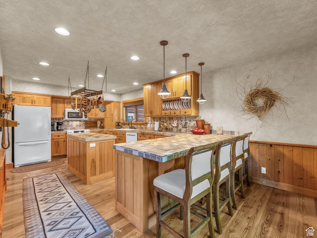 8998 Timphaven Rd, Sundance, UT 84604 - kitchen featuring white appliances, light wood-type flooring, a kitchen island, light countertops, and a wainscoted wall