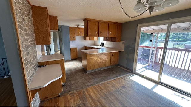 4220 S 2075 W, Roy, UT 84067 - kitchen featuring brown cabinets, a peninsula, dark wood-type flooring, light countertops, and a textured ceiling