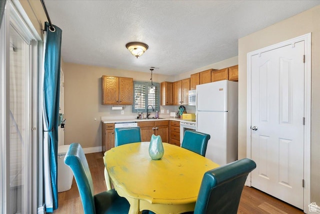 3042 S Festival Dr W, West Valley City, UT 84120 - kitchen with white appliances, wood finished floors, light countertops, brown cabinets, and pendant lighting