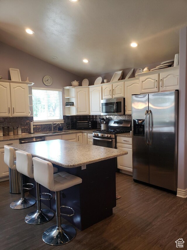 62 S 100 E, Kaysville, UT 84037 - kitchen featuring appliances with stainless steel finishes, open shelves, a center island, tasteful backsplash, and a breakfast bar area