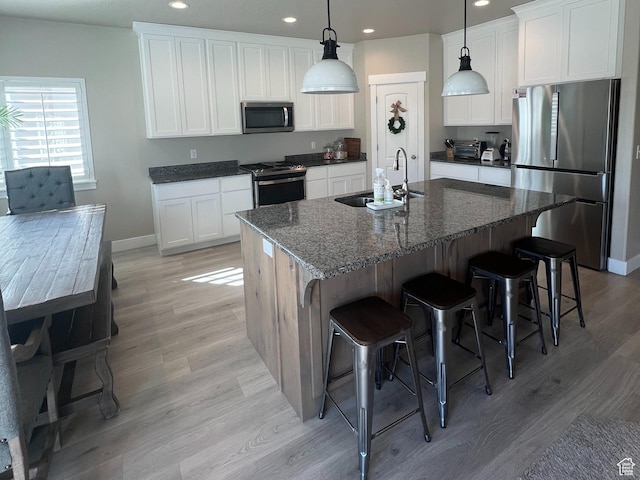 1048 N 200 E, Nephi, UT 84648 - kitchen with stainless steel appliances, recessed lighting, light wood finished floors, a breakfast bar area, and white cabinets