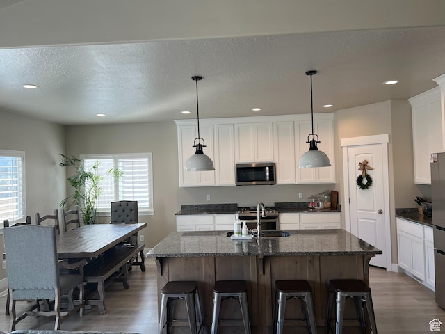 1048 N 200 E, Nephi, UT 84648 - kitchen featuring stainless steel microwave, wood finished floors, recessed lighting, a center island with sink, and white cabinets