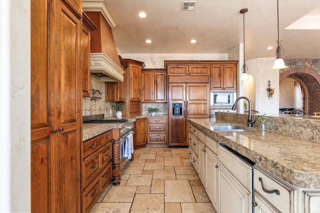 480 W Tonapah Way, Ivins, UT 84738 - kitchen featuring built in appliances, stone tile flooring, custom range hood, arched walkways, and brown cabinets