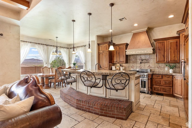 480 W Tonapah Way, Ivins, UT 84738 - kitchen featuring custom exhaust hood, stainless steel range, stone tile floors, brown cabinetry, and a kitchen breakfast bar