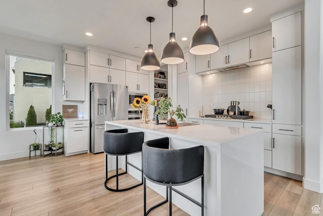 11536 S Allerton Dr, South Jordan, UT 84009 - kitchen featuring appliances with stainless steel finishes, light countertops, backsplash, a breakfast bar area, and a kitchen island