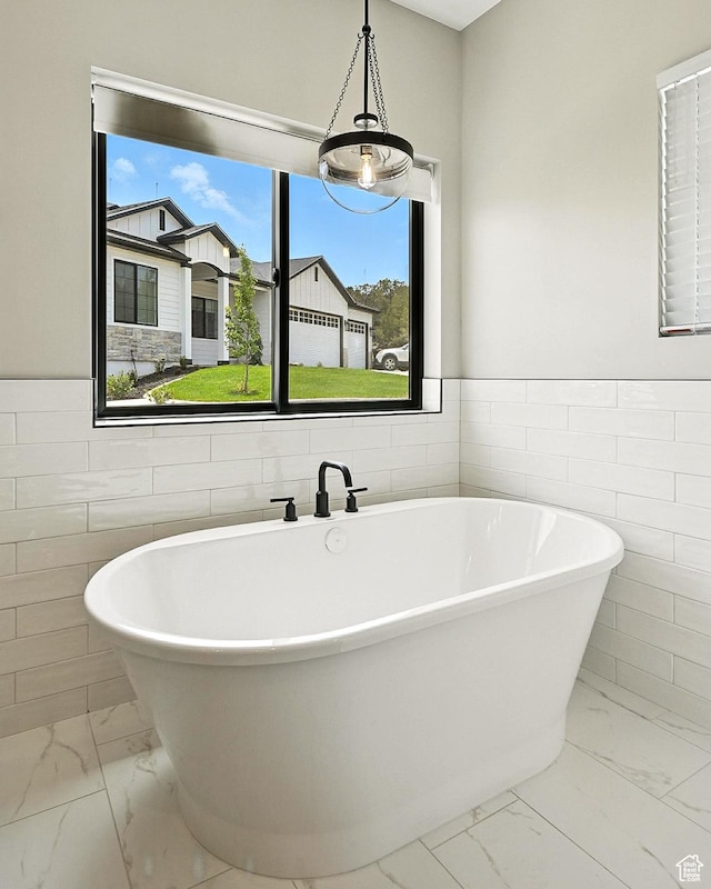 3127 W 2350 S, Cedar City, UT 84720 - bathroom with marble look tile flooring, tile walls, a freestanding bath, and a wainscoted wall