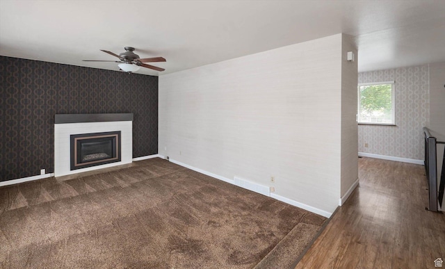 6871 S Alfalfa Cir, West Jordan, UT 84084 - unfurnished living room featuring wallpapered walls, ceiling fan, a glass covered fireplace, and wood finished floors