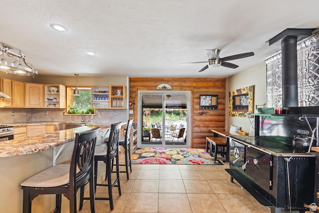 986 E 2290 N, Monroe, UT 84754 - kitchen featuring log walls, light brown cabinetry, a wood stove, open shelves, and a ceiling fan