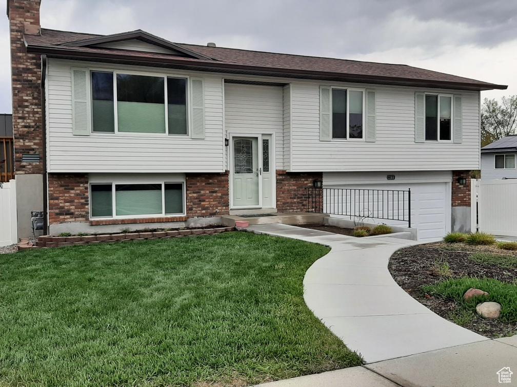 2165 W Tierra Rose Dr, Taylorsville, UT 84129 - raised ranch featuring brick siding, a front lawn, and a chimney