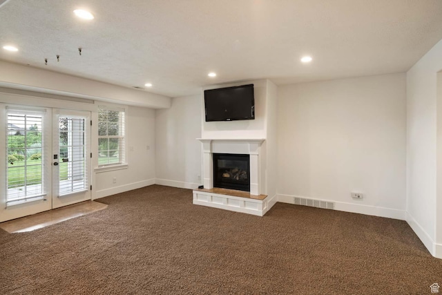 5843 W Wildflower Ln, Highland, UT 84003 - unfurnished living room featuring dark colored carpet, recessed lighting, french doors, and a glass covered fireplace