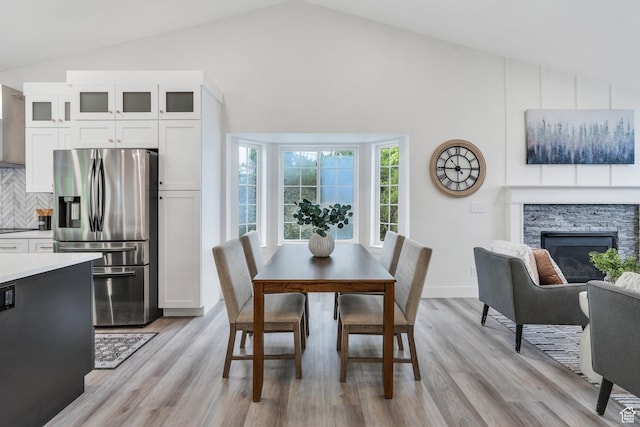 12060 S Lampton Dr W, Riverton, UT 84065 - dining space featuring lofted ceiling, light wood-style flooring, and a fireplace