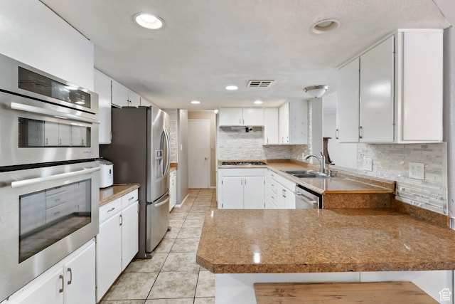 283 S 400 W, Hurricane, UT 84737 - kitchen with appliances with stainless steel finishes, a peninsula, light tile patterned flooring, white cabinets, and backsplash