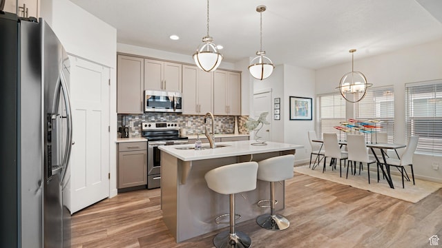 319 N 750 E, Vineyard, UT 84059 - kitchen with appliances with stainless steel finishes, tasteful backsplash, light wood finished floors, an island with sink, and gray cabinets
