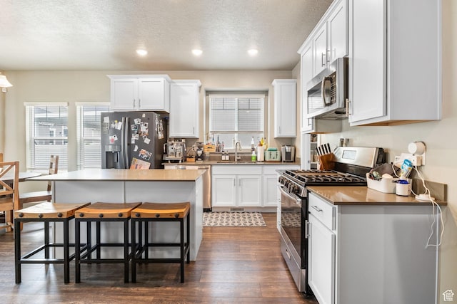 2319 N Penstemon Way, Lehi, UT 84043 - kitchen with stainless steel appliances, a kitchen breakfast bar, healthy amount of natural light, dark wood-type flooring, and a textured ceiling
