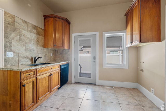1145 Kensington Ave, Salt Lake City, UT 84105 - kitchen with black dishwasher, brown cabinetry, light stone counters, and backsplash