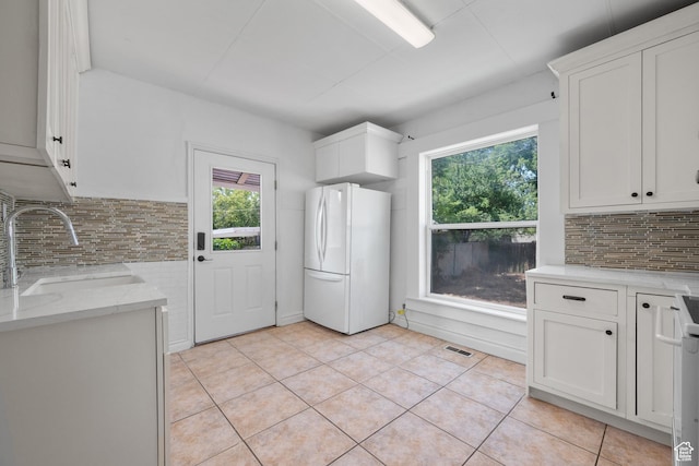 1145 Kensington Ave, Salt Lake City, UT 84105 - kitchen featuring freestanding refrigerator, backsplash, light tile patterned floors, and white cabinetry