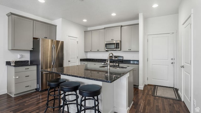 5681 W Pelican Ridge Ln, Salt Lake City, UT 84118 - kitchen with appliances with stainless steel finishes, gray cabinets, dark wood finished floors, a kitchen bar, and recessed lighting