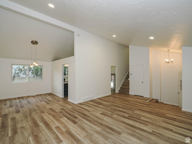 9971 S Borg Dr, Sandy, UT 84092 - unfurnished living room with a chandelier, lofted ceiling, stairway, light wood-style floors, and recessed lighting