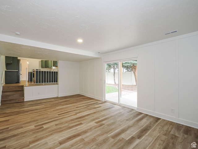 9971 S Borg Dr, Sandy, UT 84092 - unfurnished living room featuring light wood-type flooring and a decorative wall