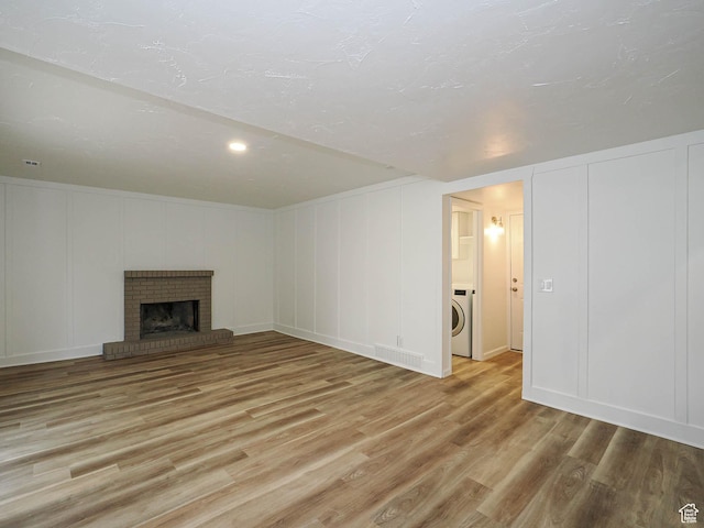 9971 S Borg Dr, Sandy, UT 84092 - unfurnished living room featuring a decorative wall, light wood-type flooring, washer / dryer, and a fireplace