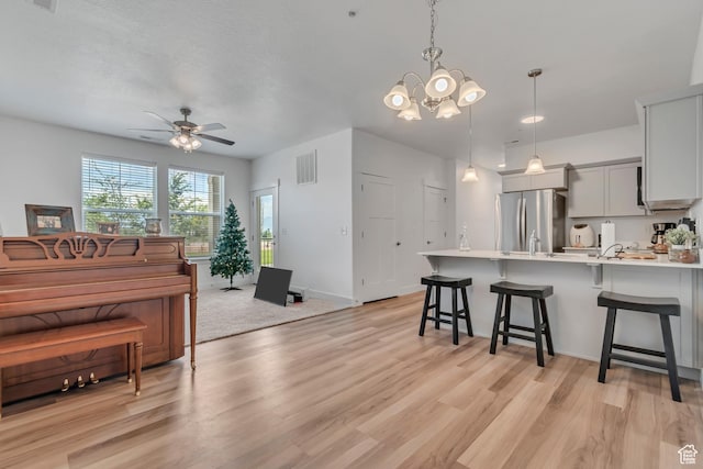 1382 N 3650 W Unit V101, Lehi, UT 84043 - kitchen featuring freestanding refrigerator, a breakfast bar, a peninsula, light countertops, and light wood-style floors