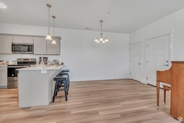1382 N 3650 W Unit V101, Lehi, UT 84043 - kitchen featuring stainless steel appliances, a breakfast bar area, gray cabinetry, and light wood-style flooring