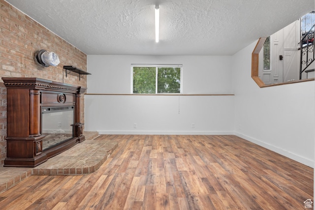 3305 W Kingsbrook Ave S Unit 148, Taylorsville, UT 84129 - unfurnished living room featuring a textured ceiling, hardwood / wood-style floors, and a brick fireplace