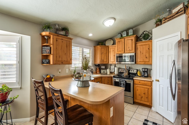 576 Mayo Dr N, Tooele, UT 84074 - kitchen featuring appliances with stainless steel finishes, light countertops, a peninsula, a breakfast bar area, and light tile patterned floors