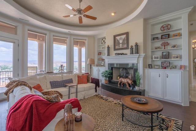 16 N Lions Head Cir, Washington, UT 84780 - living room featuring built in features, a ceiling fan, a fireplace, wood finished floors, and a raised ceiling