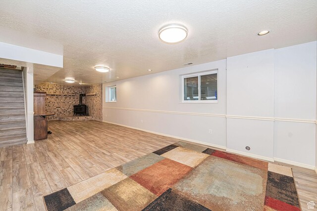 5883 S Jared Way E, South Ogden, UT 84403 - below grade area featuring stairway, a textured ceiling, a wood stove, and wood finished floors