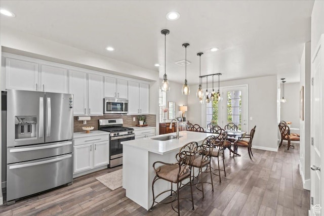 5328 W S Jordan Pkwy S, South Jordan, UT 84009 - kitchen with appliances with stainless steel finishes, backsplash, light countertops, white cabinetry, and wood finished floors
