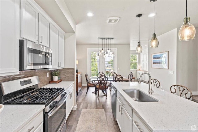 5328 W S Jordan Pkwy S, South Jordan, UT 84009 - kitchen featuring appliances with stainless steel finishes, wood finished floors, a center island with sink, white cabinets, and tasteful backsplash