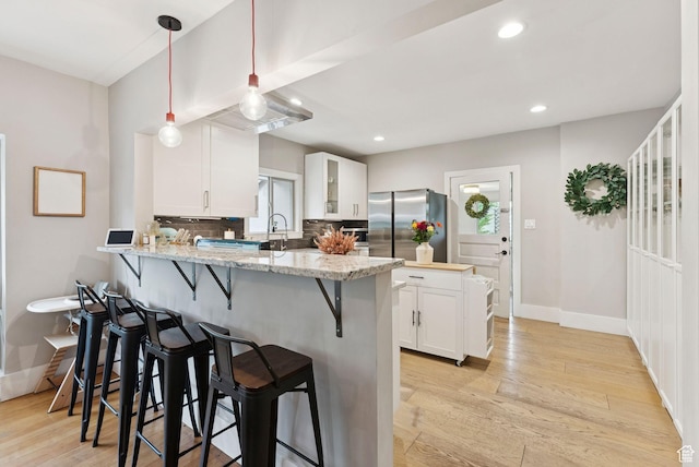 1873 S Lincoln St E, Salt Lake City, UT 84105 - kitchen with freestanding refrigerator, a kitchen bar, a peninsula, white cabinetry, and glass insert cabinets