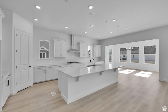 1147 S 3170 E Unit 207, Spanish Fork, UT 84660 - kitchen with wall chimney exhaust hood, an island with sink, recessed lighting, light wood-style flooring, and white cabinets