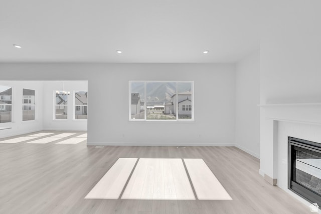 1147 S 3170 E Unit 207, Spanish Fork, UT 84660 - unfurnished living room featuring a glass covered fireplace, light wood-style flooring, a chandelier, and recessed lighting