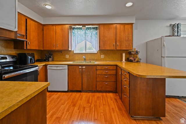 308 W 1050 N, Logan, UT 84321 - kitchen featuring white appliances, a peninsula, light wood-style flooring, light countertops, and a textured ceiling