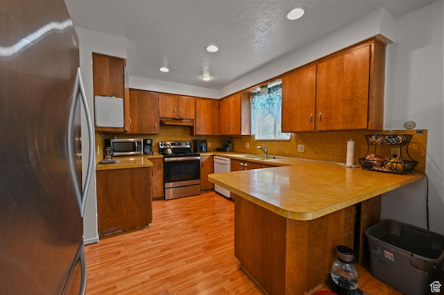 308 W 1050 N, Logan, UT 84321 - kitchen with stainless steel appliances, ventilation hood, a peninsula, light wood-type flooring, and brown cabinetry