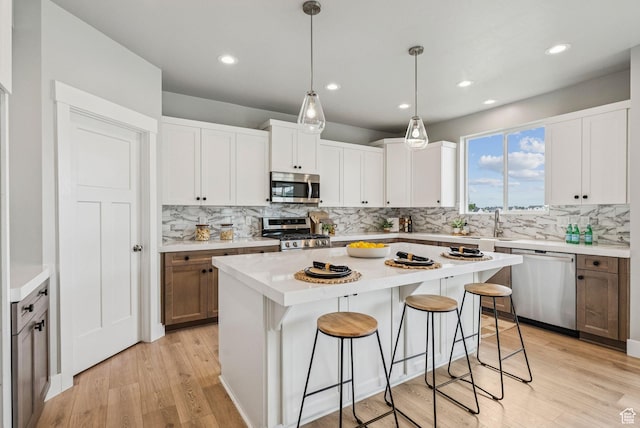 4269 W 2025 S, West Haven, UT 84401 - kitchen featuring stainless steel appliances, a breakfast bar, decorative backsplash, light wood-type flooring, and light countertops