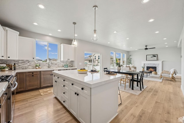 4269 W 2025 S, West Haven, UT 84401 - kitchen with stainless steel gas stove, recessed lighting, decorative backsplash, light countertops, and a lit fireplace