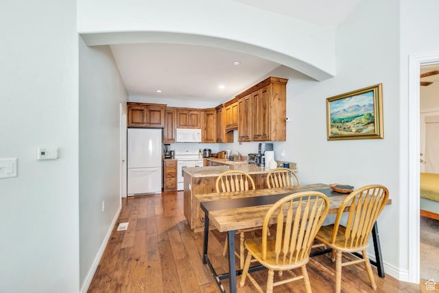 588 S 350 E, Pleasant Grove, UT 84062 - kitchen with white appliances, brown cabinetry, a peninsula, light countertops, and wood-type flooring