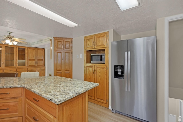 192 N Highland Blvd, Brigham City, UT 84302 - kitchen featuring appliances with stainless steel finishes, light wood finished floors, light stone counters, ceiling fan, and a textured ceiling