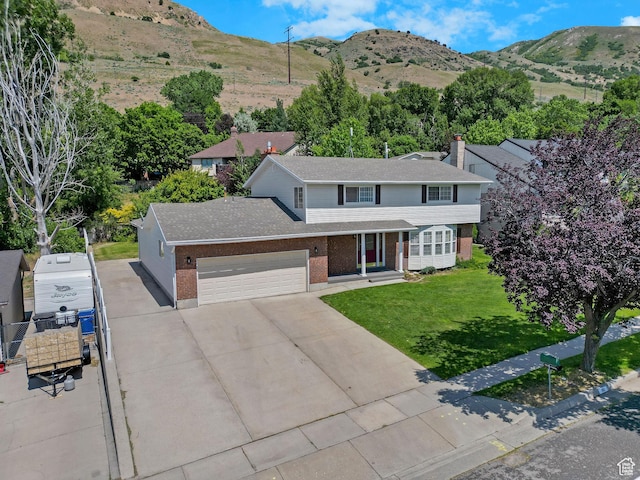 192 N Highland Blvd, Brigham City, UT 84302 - traditional home featuring brick siding, an attached garage, concrete driveway, a front yard, and a mountain view