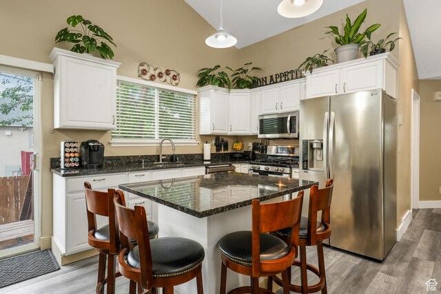 3561 S Jenelles Bay, West Valley City, UT 84119 - kitchen featuring stainless steel appliances, white cabinetry, a breakfast bar, light wood-style floors, and high vaulted ceiling