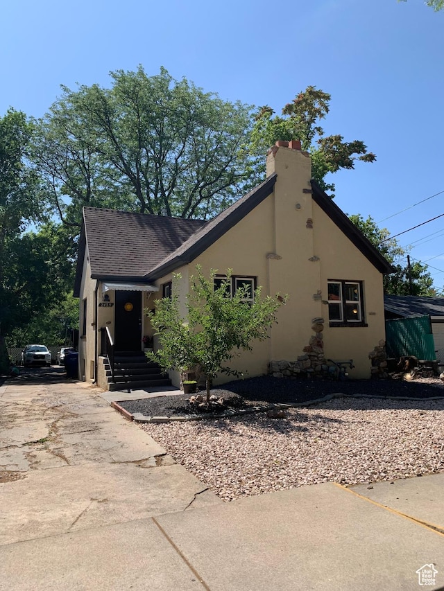 2425 Van Buren Ave, Ogden, UT 84401 - view of front of home with stucco siding, a chimney, and roof with shingles